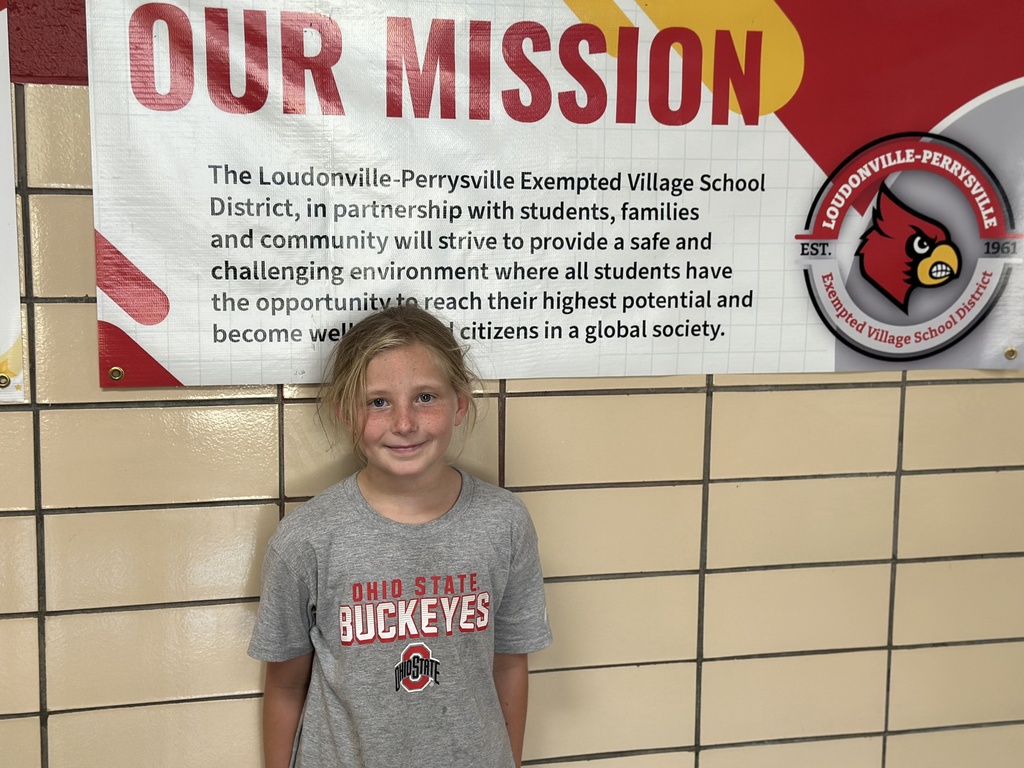 Photo of Raegan infront of a mission banner. 