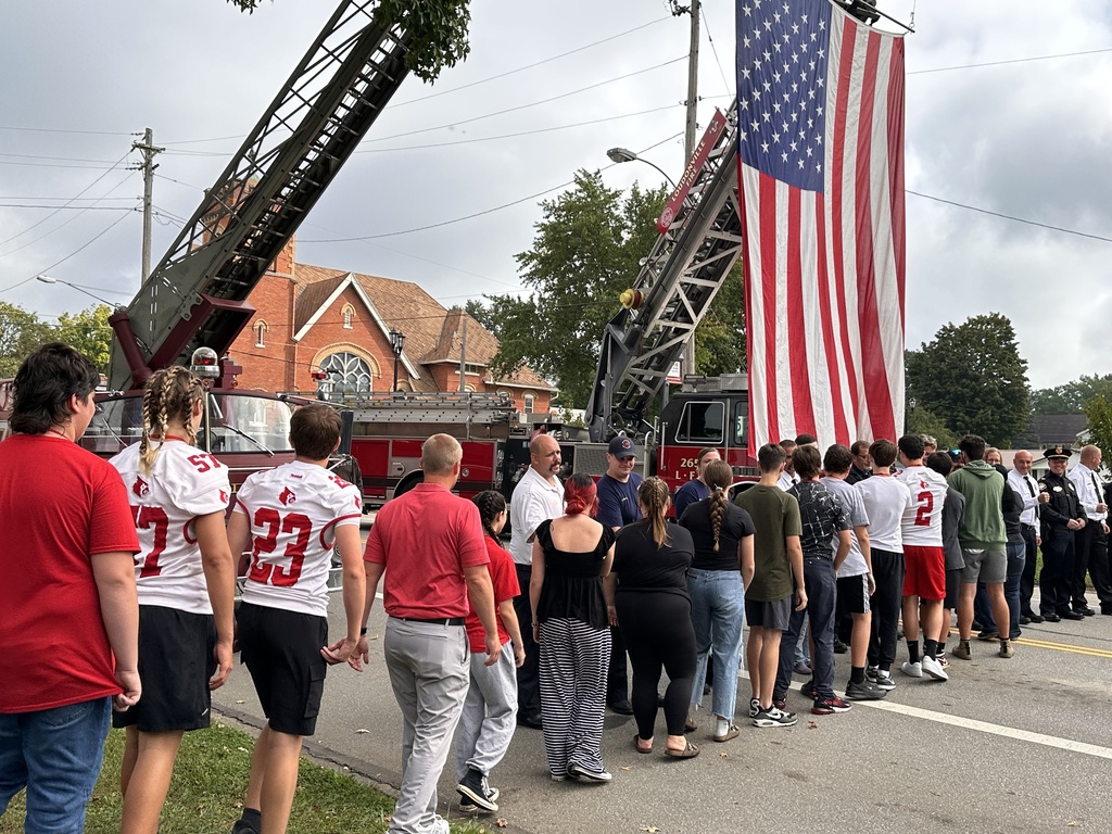 Line of students thanking first responders in front of fire truck flying the American flag. 