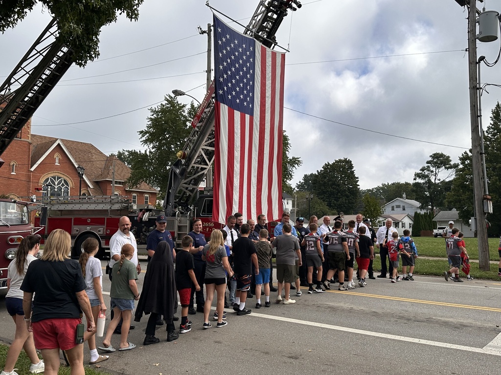 Line of students thanking first responders in front of fire truck flying the American flag. 
