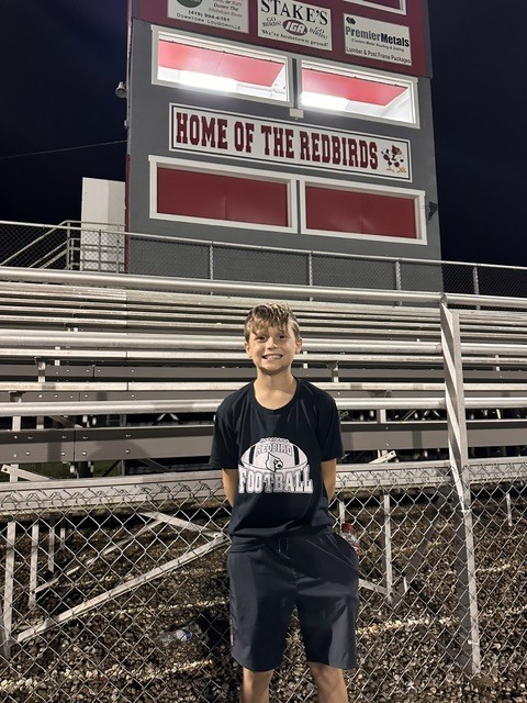 Kaeden standing infront of the bleachers for a photo. 