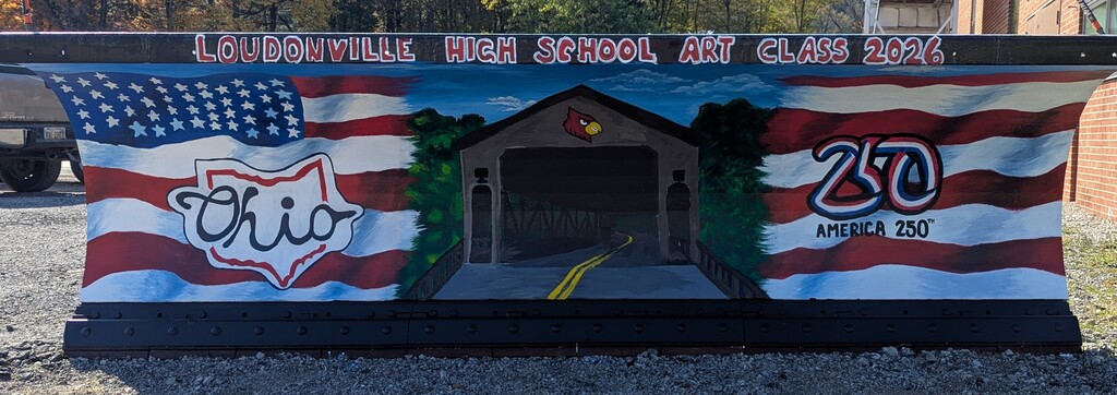 Photo of the student artwork painted on the plow representing America's 250th birthday and a covered bridge in the Mohican State Park.