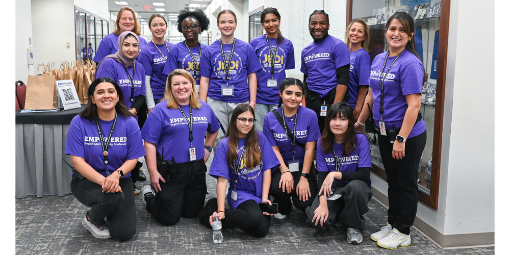 Group of people wearing matching purple 'EMPOWERED' t-shirts posing indoors in a professional setting.