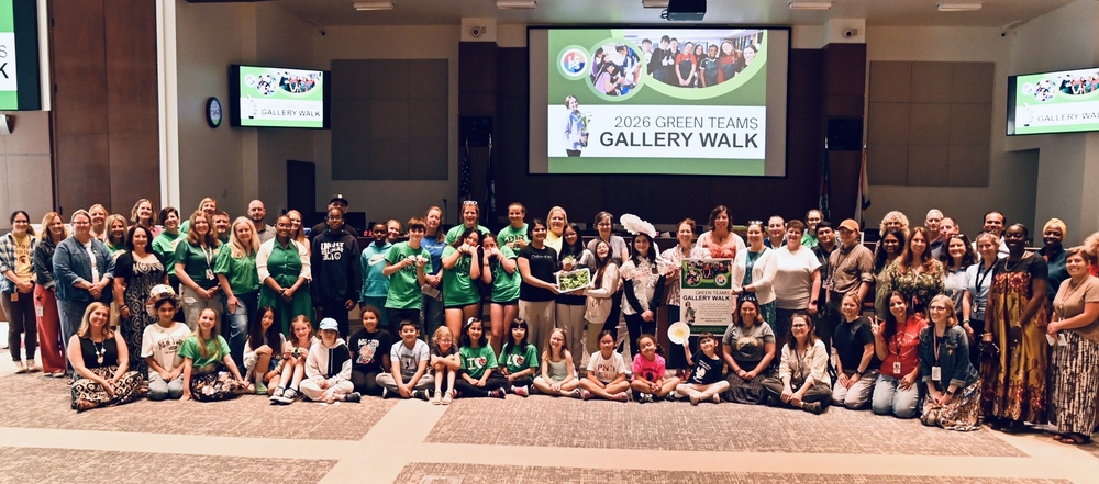 Students, staff and community members pose together in front of a presentation screen at the 2026 Green Teams Gallery Walk, where sustainability projects were showcased.