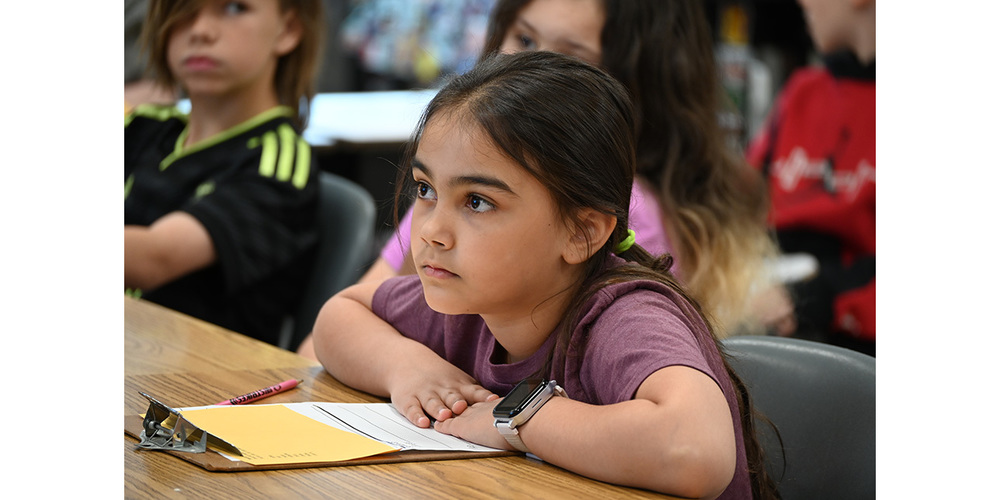 Young girl sitting at a table looking off camera
