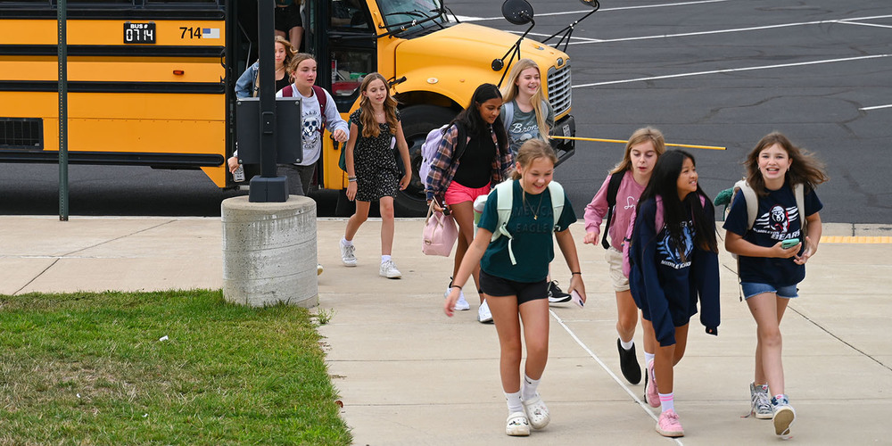 A group of female students walking off of a school bus.