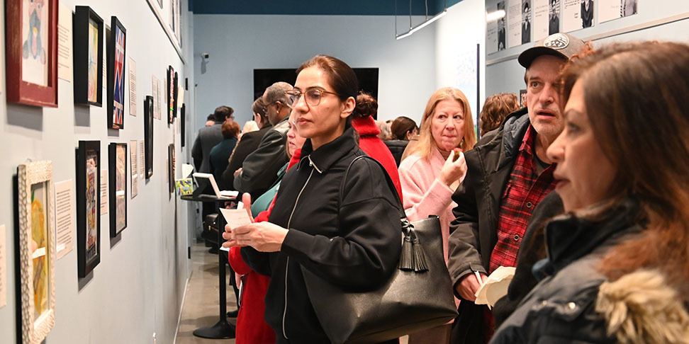 A group of adults looking at various  art pieces on display