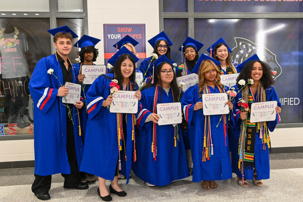 CAMPUS seniors in blue caps and gowns pose together during a graduation celebration.