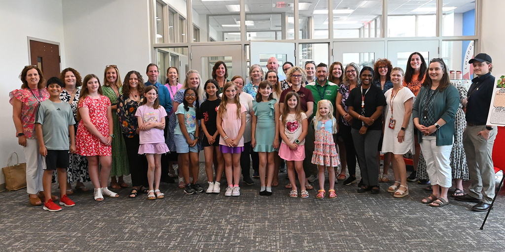 A large group of students and staff posing together in the LCPS administration office lobby.