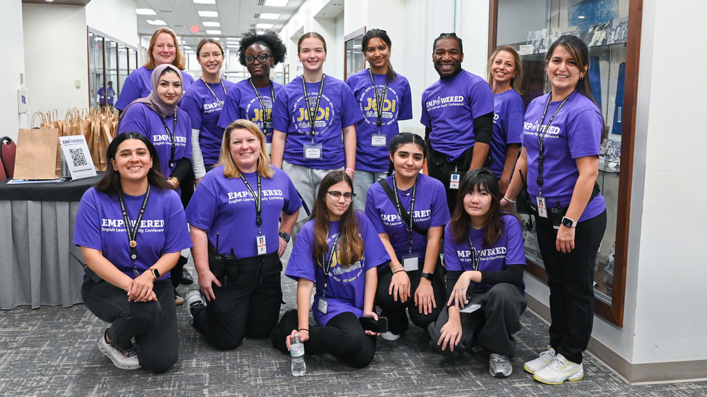 Group of people wearing matching purple 'EMPOWERED' t-shirts posing indoors in a professional setting.