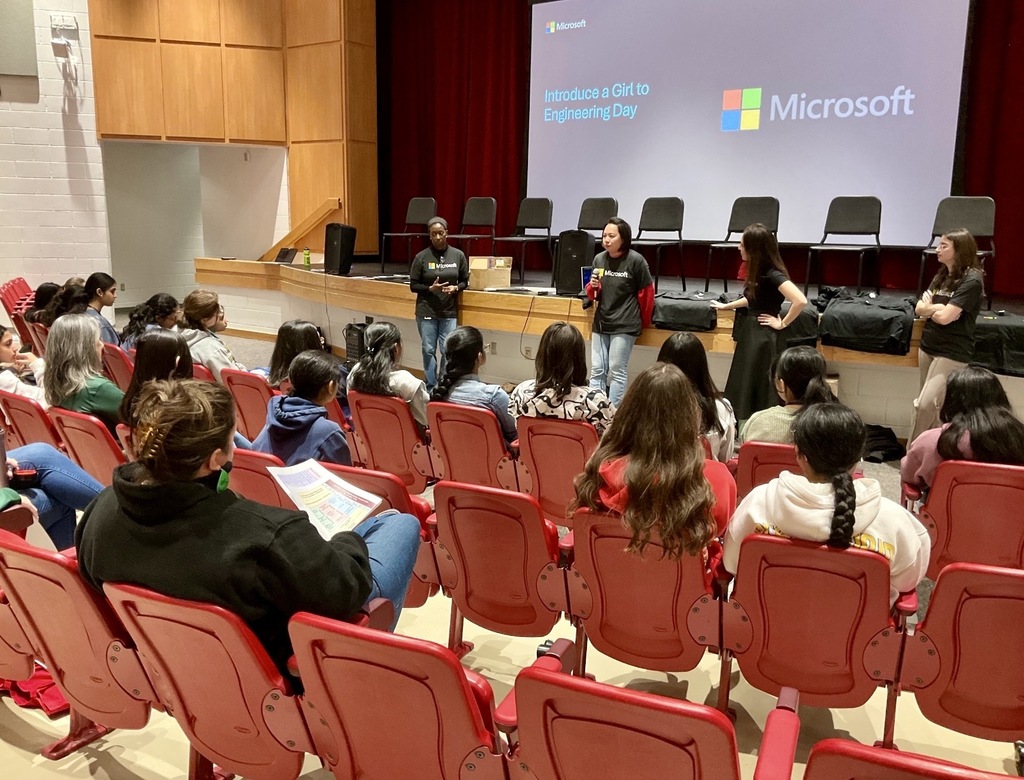 A group of young women attending a Microsoft presentation on Girls in Engineering Day in an auditorium.