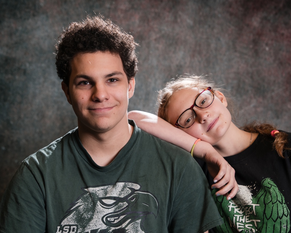 Two students smiling for a portrait, one leaning on the other