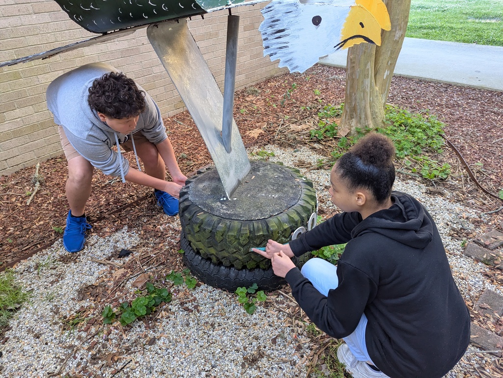 Students outside measuring a tire on a statue
