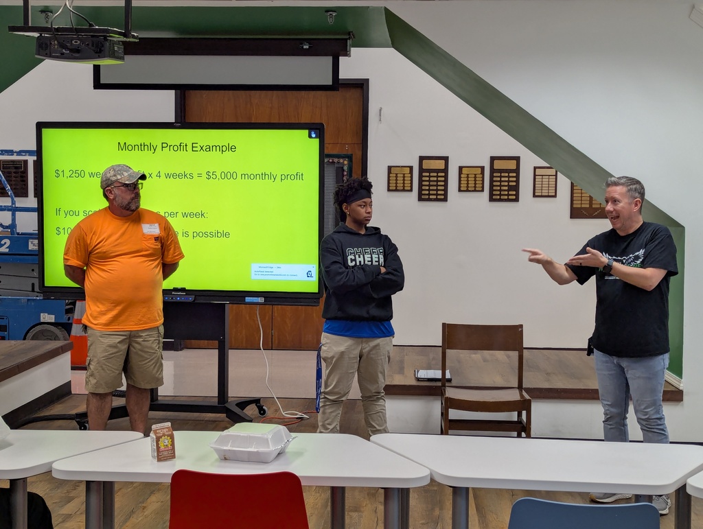 Presenter, student, and staff in front of the room discussing. 