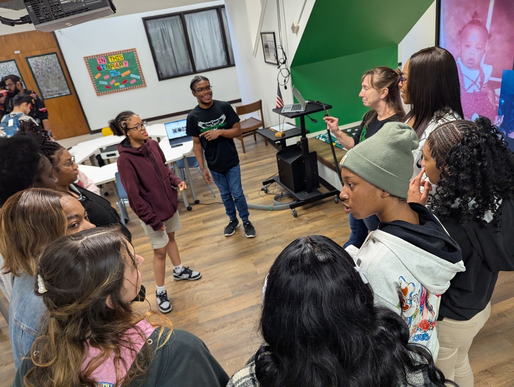 Presenter surrounded by a group of students asking questions