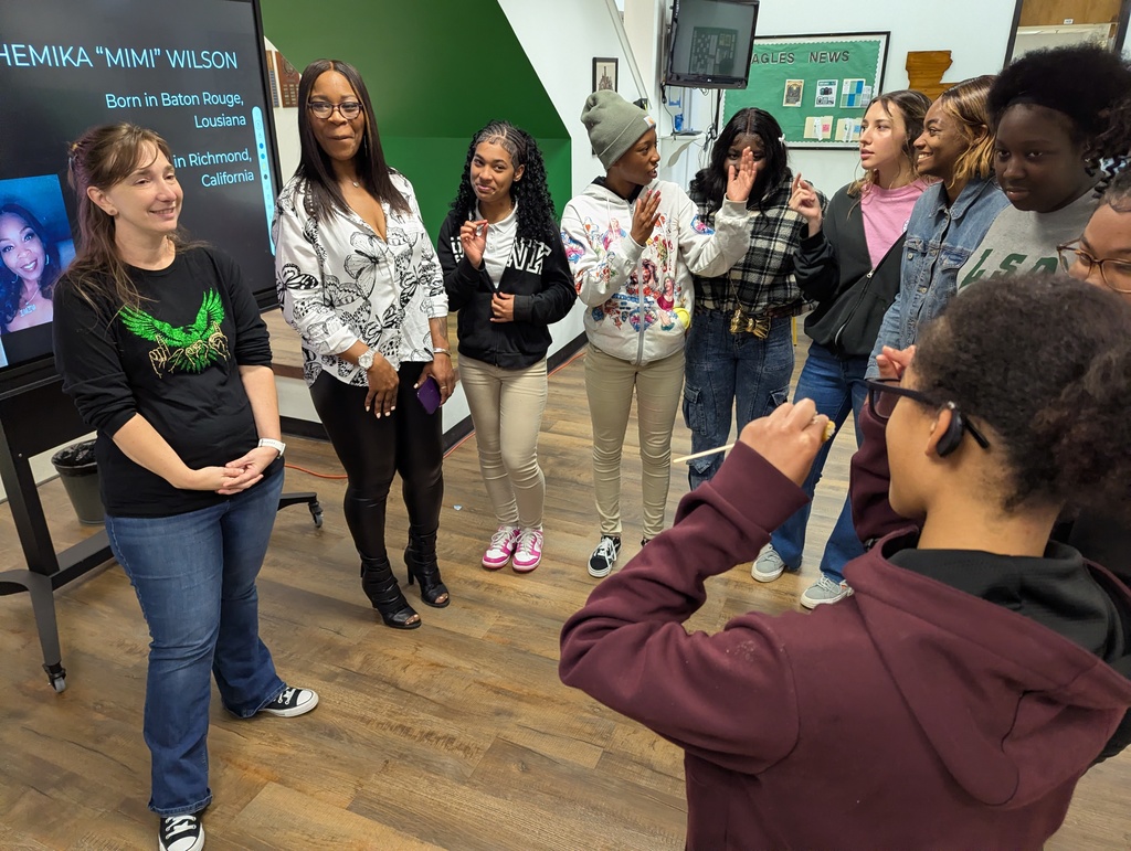 Presenter surrounded by a group of students asking questions