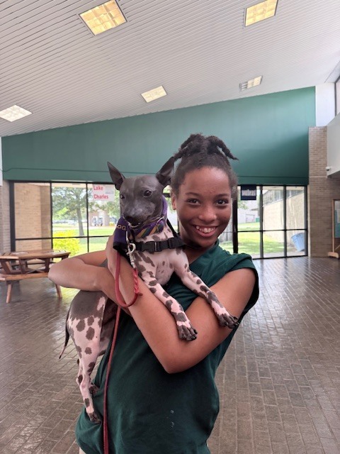 Student smiling and holding a dog
