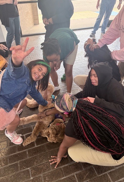 Students around a dog petting it. 