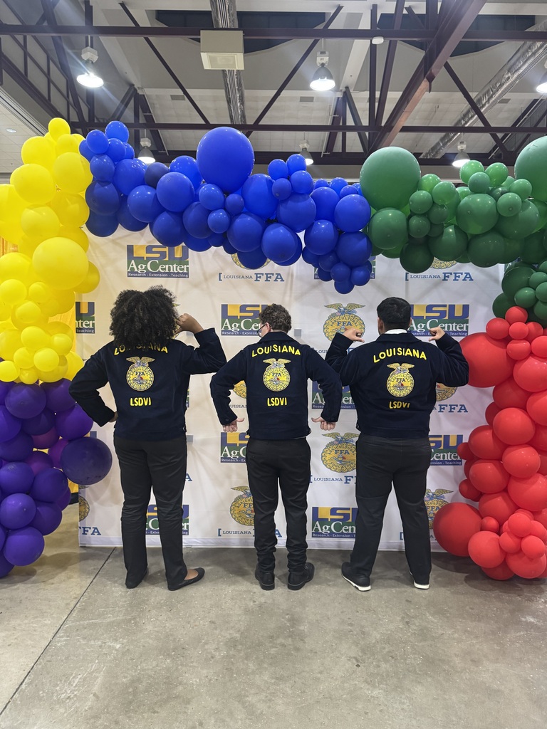 Students standing with their LSDVI FFA dress, pointing to it