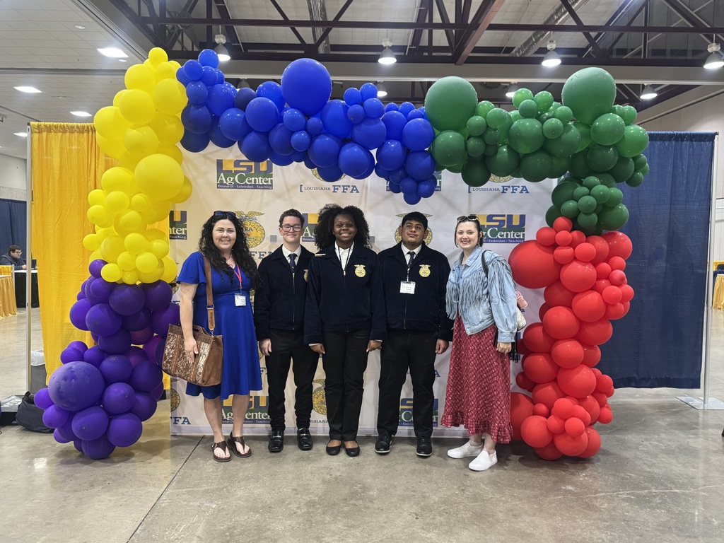 Students and staff standing in front of an FFA sign, smiling