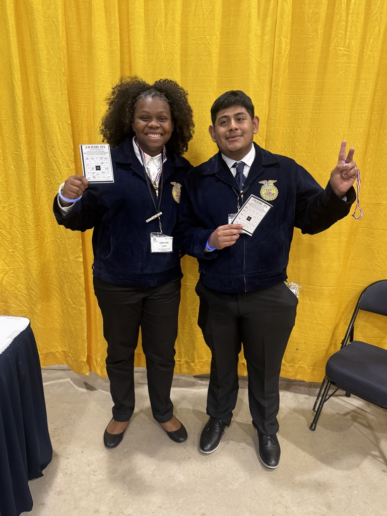 Students in FFA dress proudly holding up a bingo paper and smiling