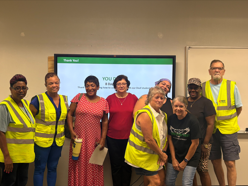 A group of people smiling in neon bus vests