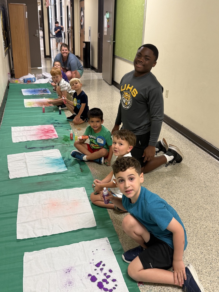 Teacher and older boy student working on tie die project with little boy campers