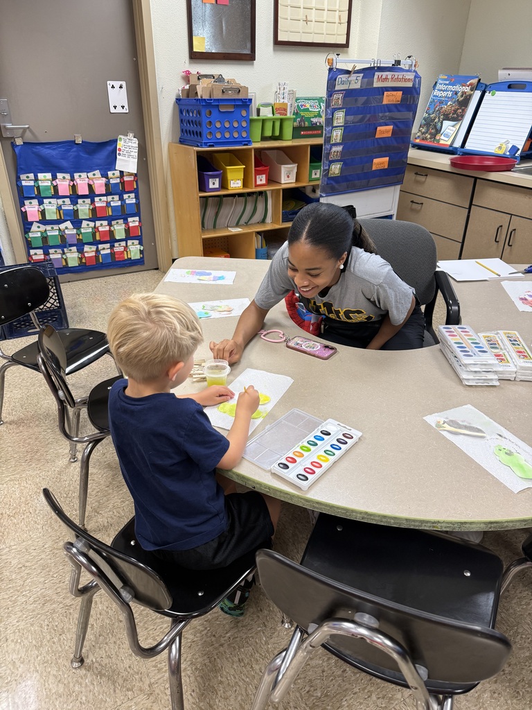 Girl camp counselor assisting boy elementary student with art project