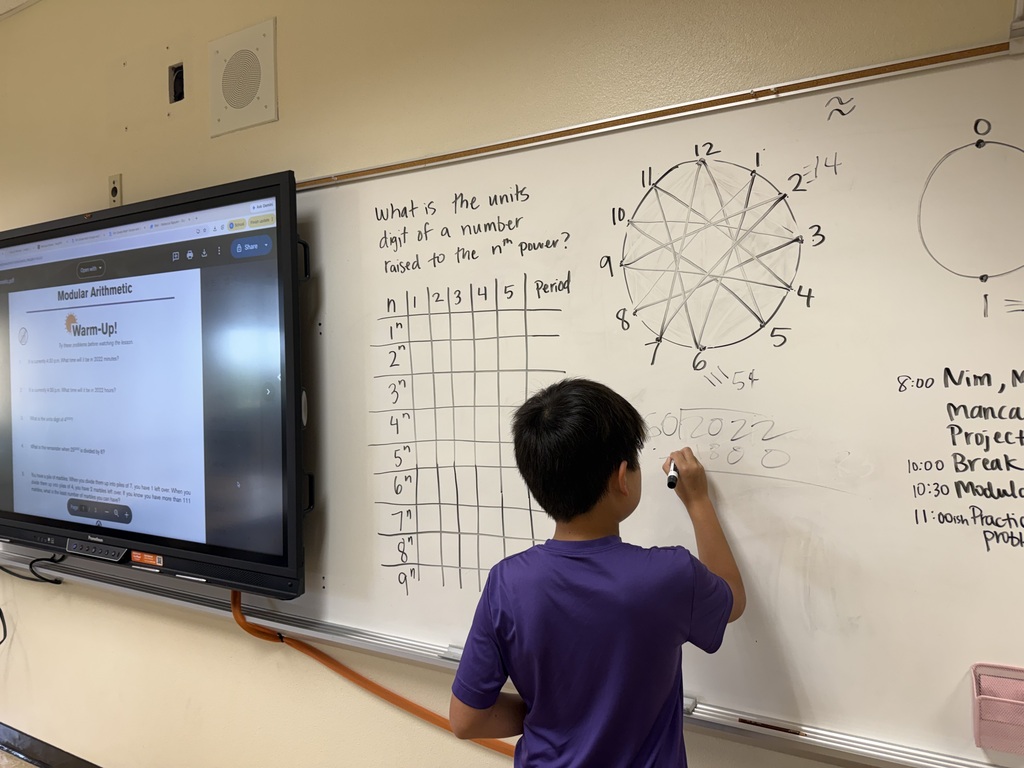 male student facing dry erase board working on math problems