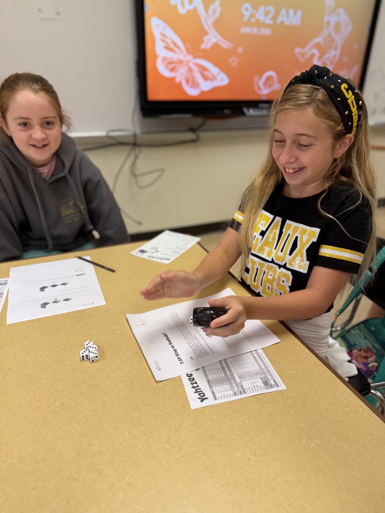 girls smiling in classroom at a table while working on math problems