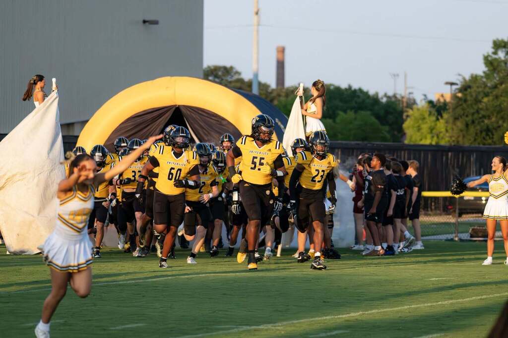 football team running out of tunnel on a sunny day at the football field