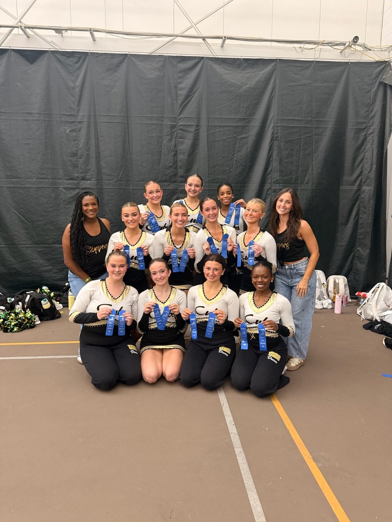 Girl dancers  and coached posed with blue ribbons  