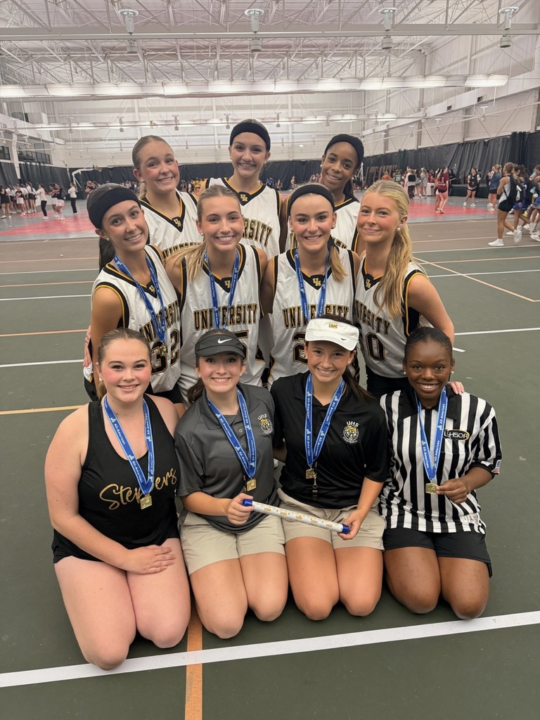 girls wearing unviersity basketball jerseys in a gym holding award with blue medals around their necks