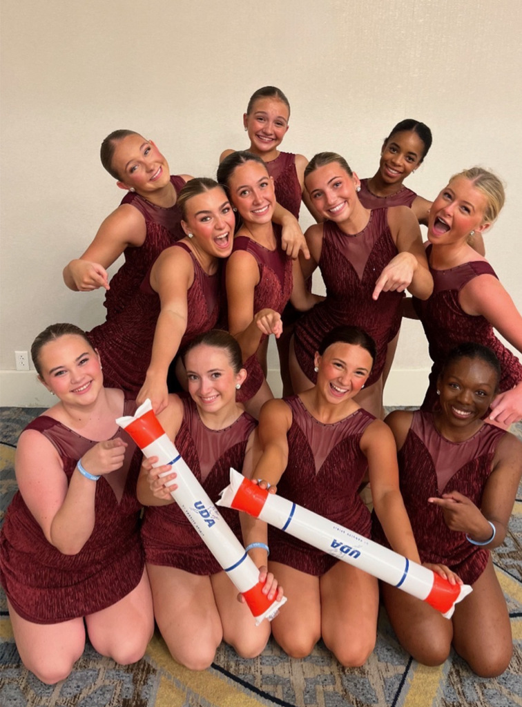 Girl dancers posed with UDA award wearing burgundy dancewear