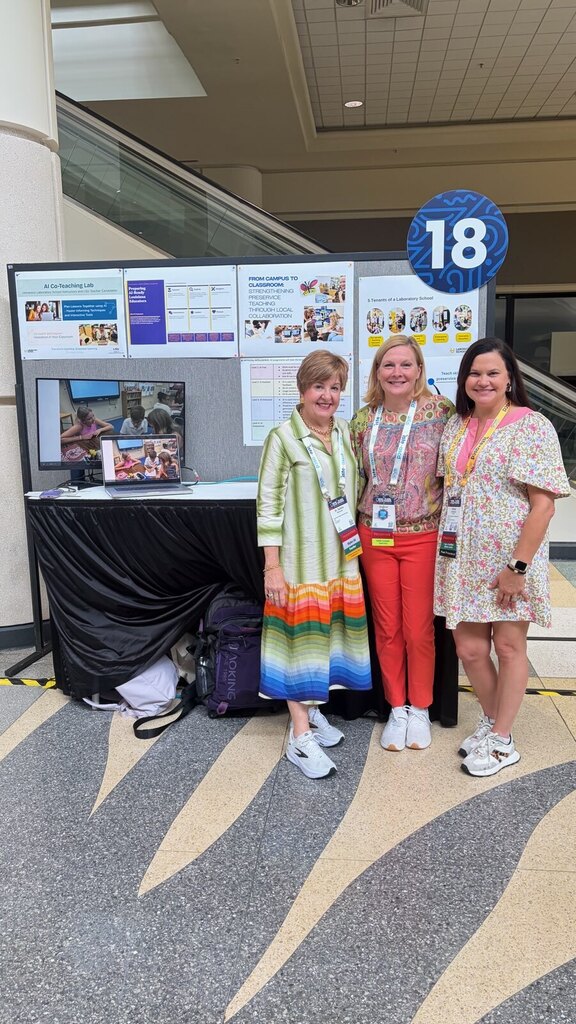 three women standing in front of a presentation board smiling at the camera