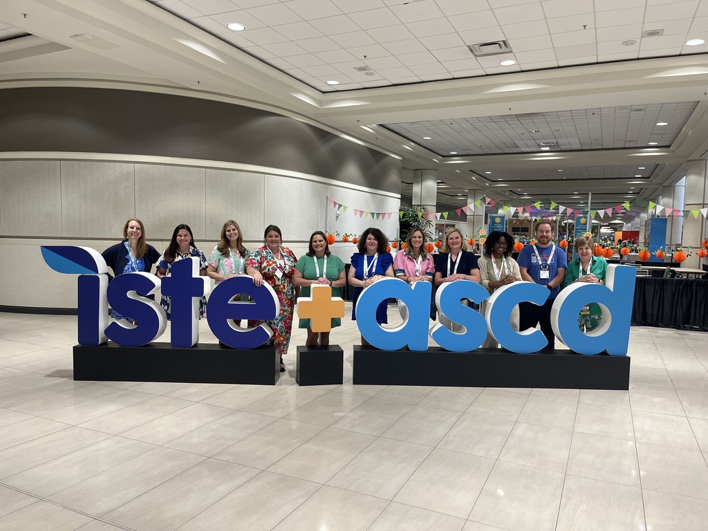 a group of men and women standing being the iste+ascd sign smiling