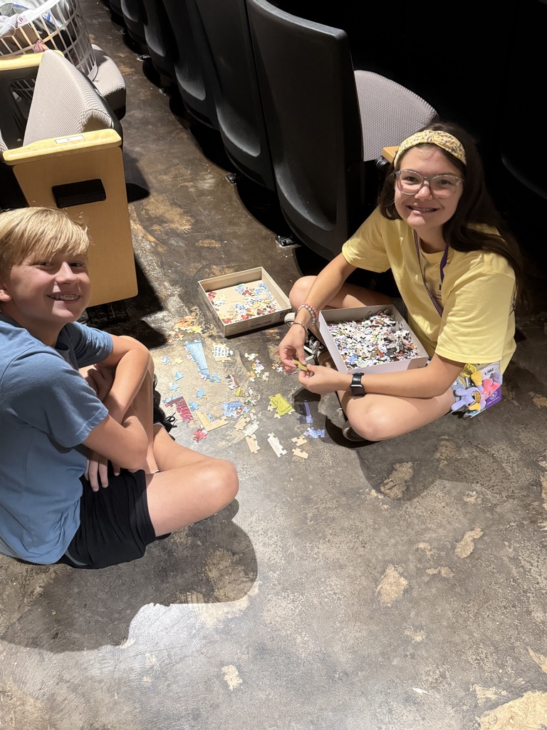 two camp students seated on the floor working on a puzzle together