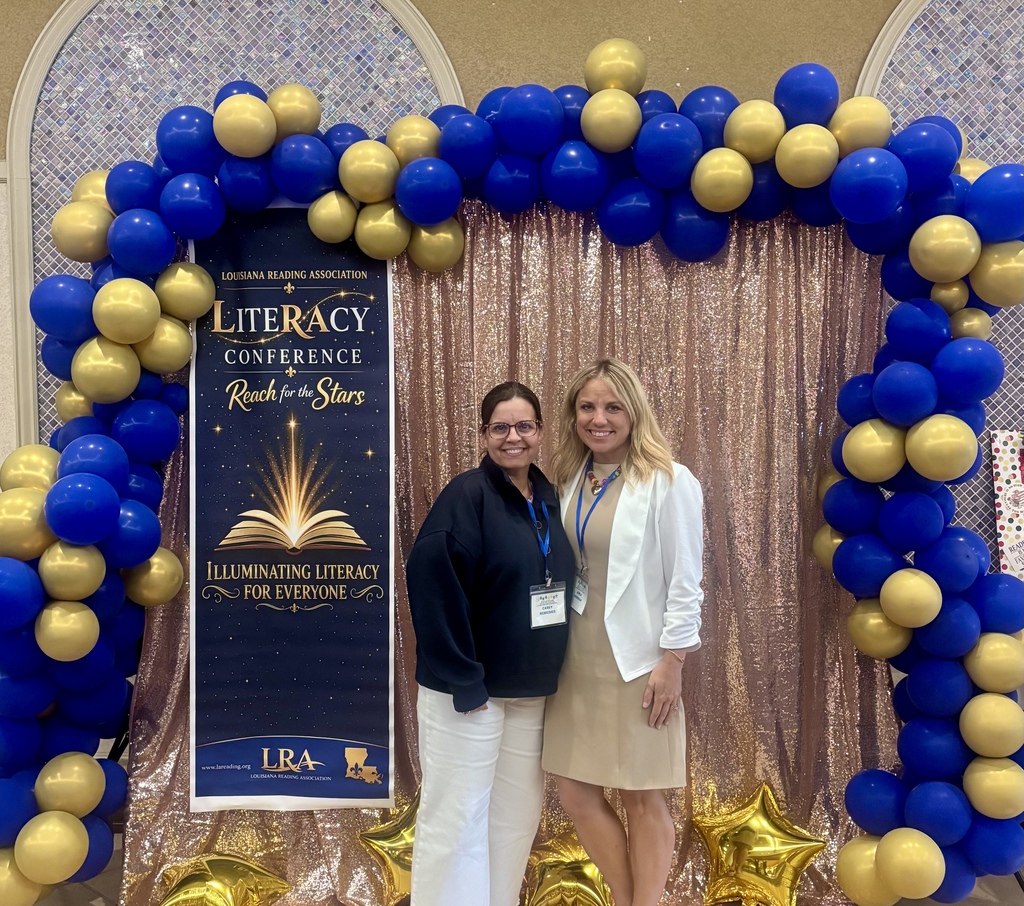 two ladies standing in between a blue and gold ballon arch posing at the camera