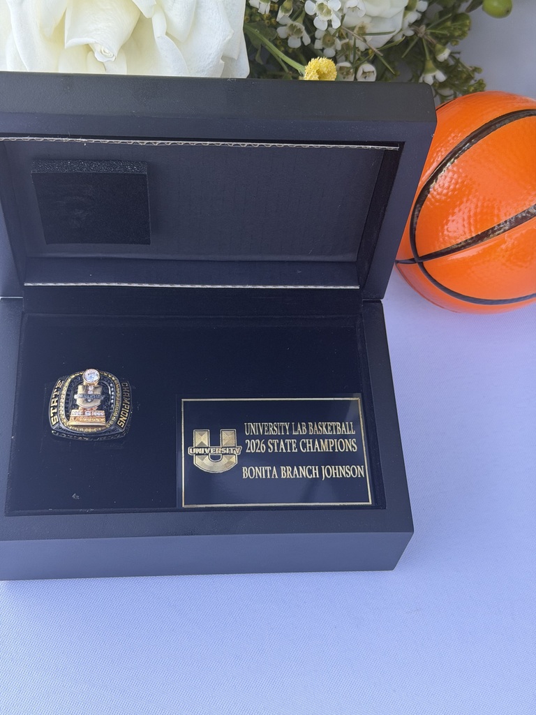 Championship ring displayed in a case on a black background with a plaque that reads "University Lab Basketball 2026 State Champions Bonita Branch Johnson"