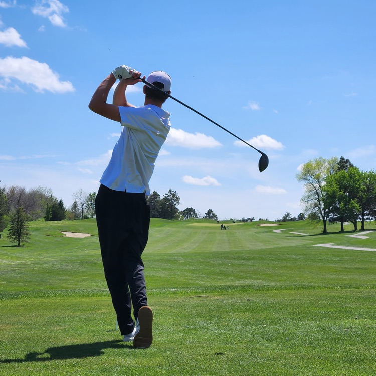 A member of the Louisville boys golf team swinging his club at a competition