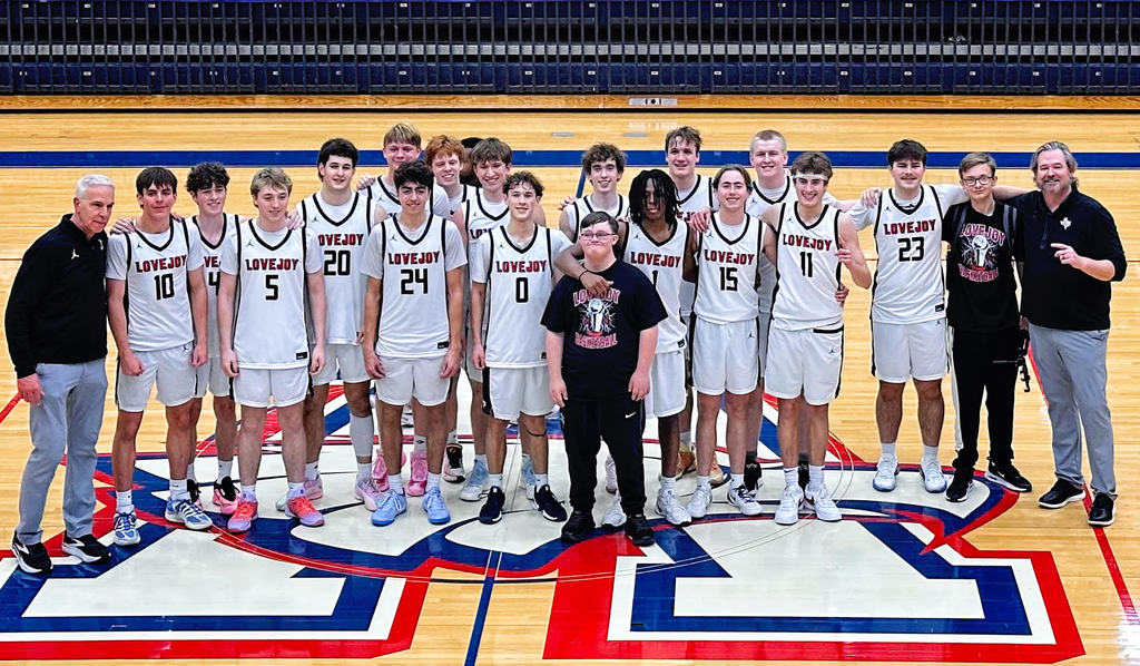 Team members wearing white jerseys pose for a team photo on a basketball court.