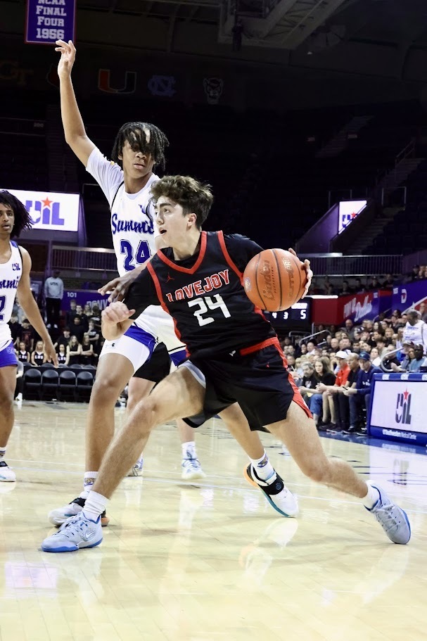 Basketball players in a gymnasium. One player wearing a black jersey with number 24 dribbles the ball. Another player wearing a white jersey with number 24 defends.