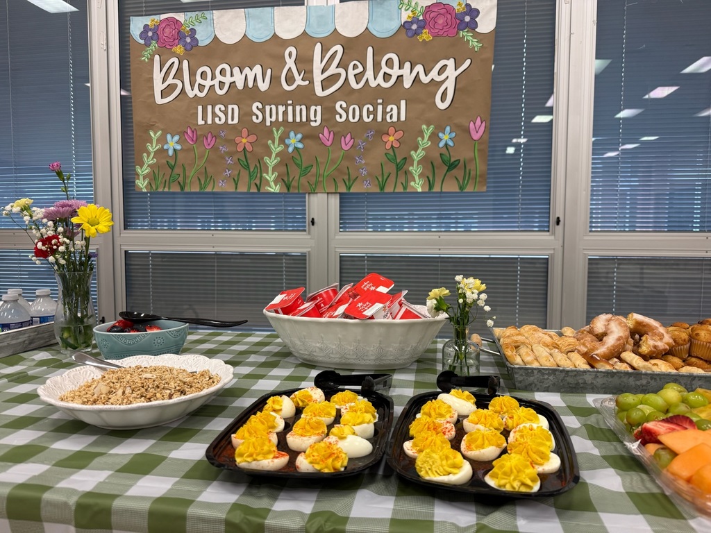 Food table for a spring social event with deviled eggs, fruit, and more. A sign above reads "Bloom & Belong LISO Spring Social."