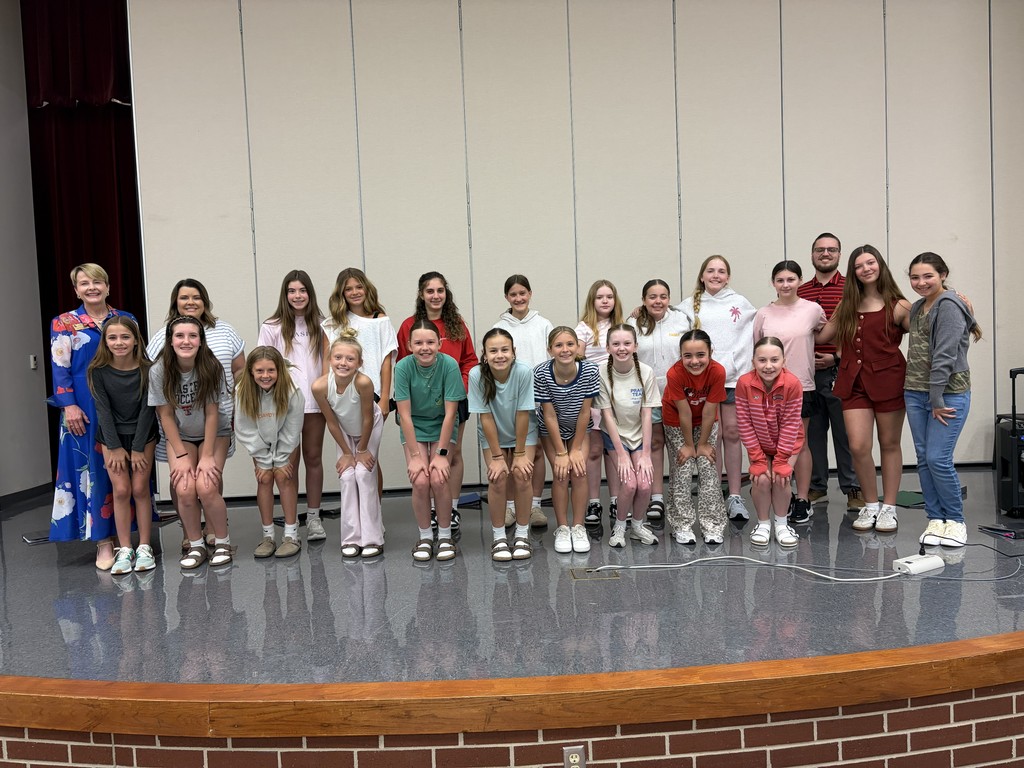 A group of people, likely a club, posing for a photo on a stage with brick base.