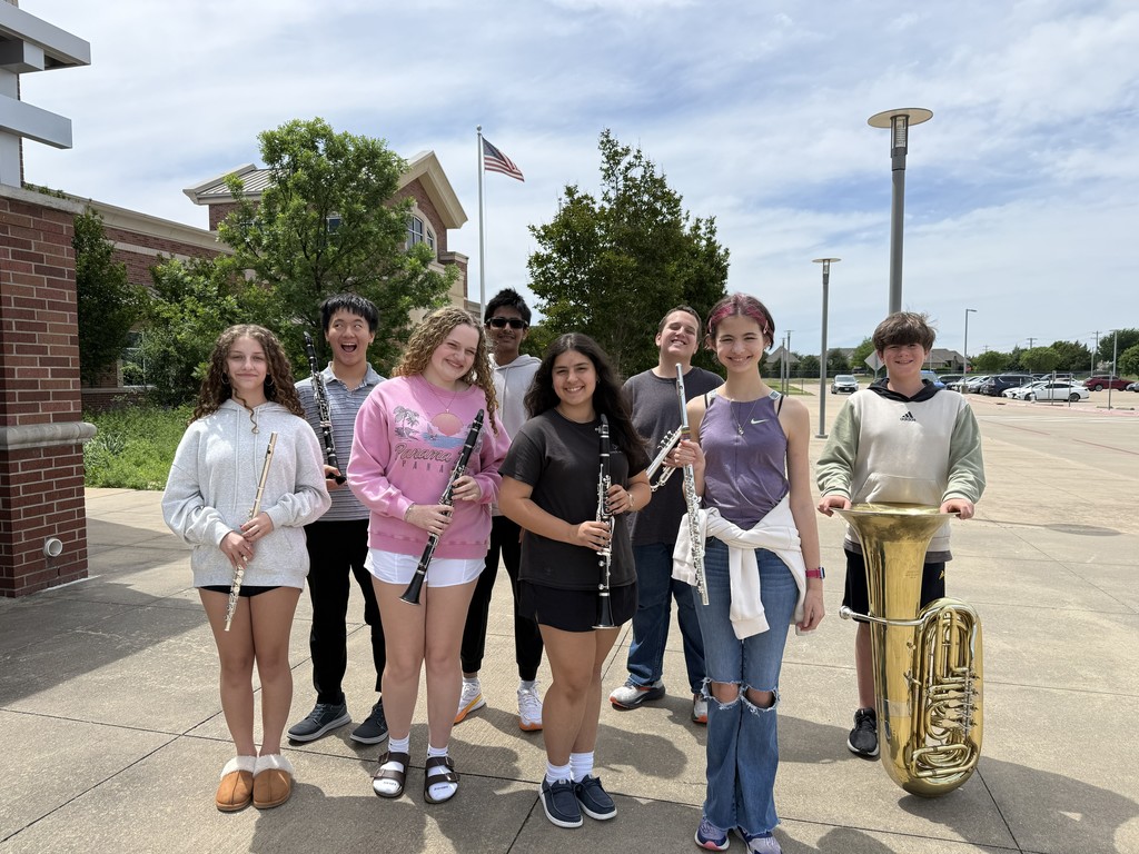 A group of young people poses outside, some holding musical instruments. A flag is visible in the background.