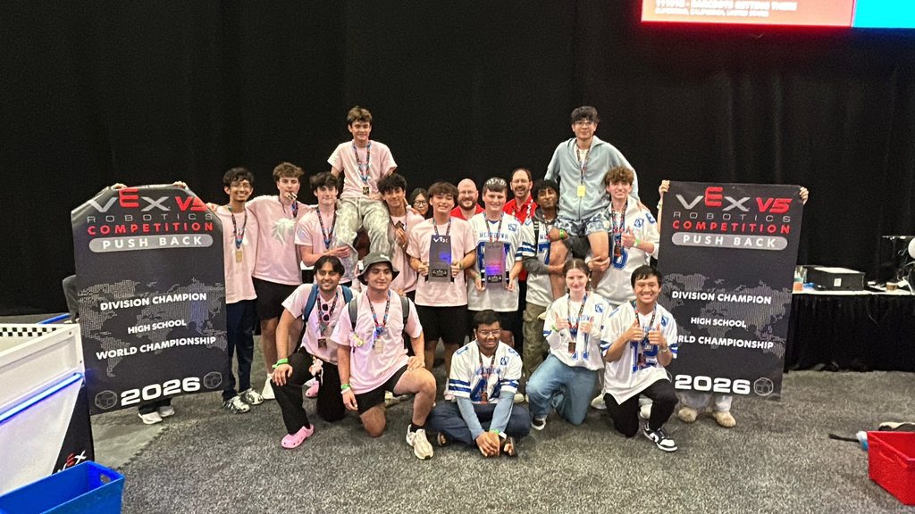 A team poses for a photo with medals and banners that read "VEX Championship 2026".