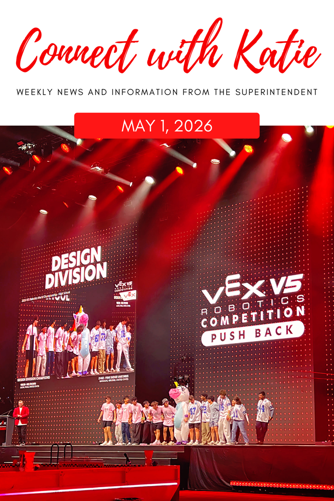 A stage with a red background, large screens showing a design competition and robots, and a group of individuals standing.