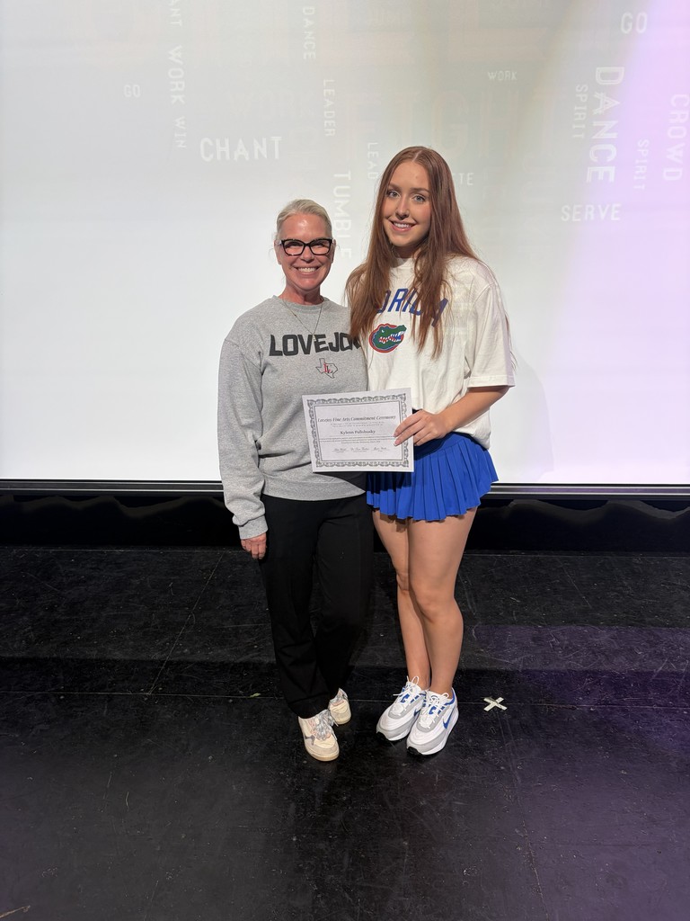 Two people on a stage, one holding a certificate, with a projector screen in the background.