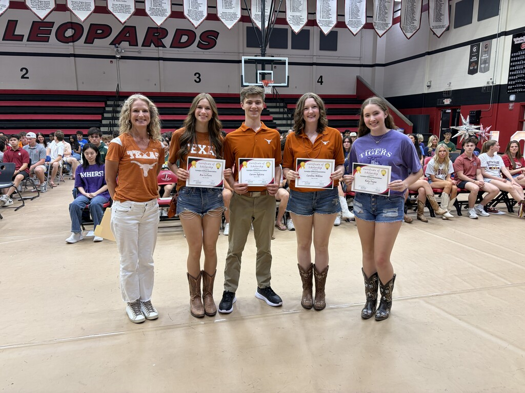 Five young people hold certificates in a gymnasium. A crowd sits behind them. Banners hang from the ceiling, one reading "Leopards."