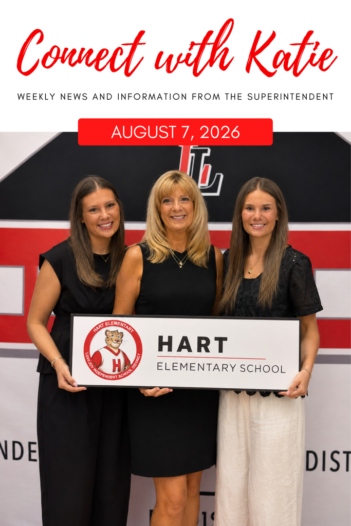 Three women stand behind a banner with the text "Hart Elementary School". The middle woman holds a sign.