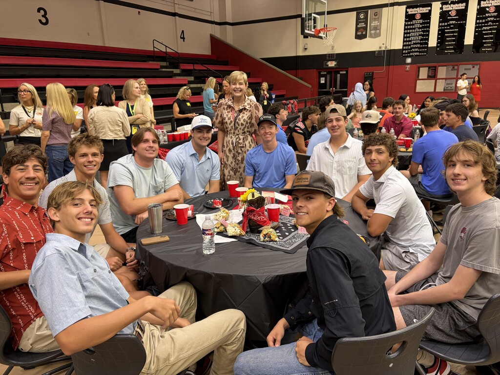A group of people, including men and women, sitting around a table in a school cafeteria.